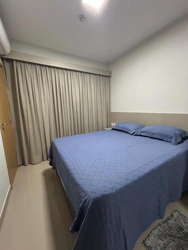 a bedroom with a blue bed and a window at Park Veredas - Flat 216 in Rio Quente
