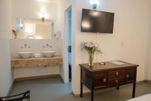 a bathroom with two sinks and a vase of flowers on a table at San Telmo Petit Hotel in Buenos Aires