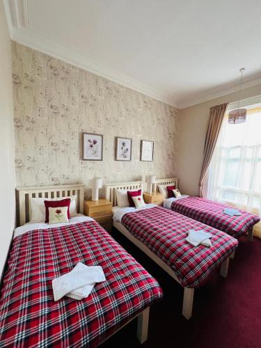 a bedroom with two beds with red and white blankets at Thistle Residence in Edinburgh