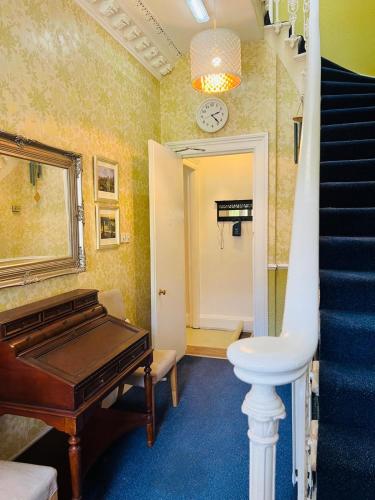 a hallway with a piano and stairs with a clock at Thistle Residence in Edinburgh