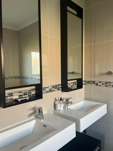 a bathroom with two sinks and two mirrors at At the 5th in Langebaan