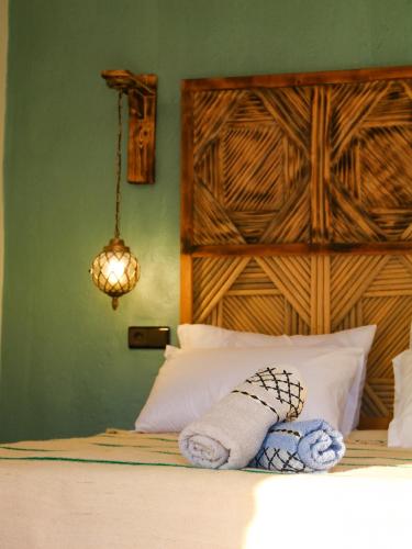 a bed with a wooden headboard and a towel on it at auberge Brava Tifnit 