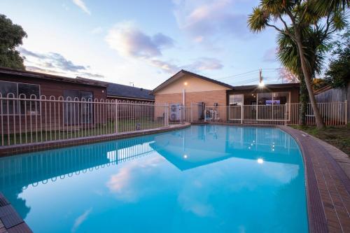 a swimming pool with blue water in front of a house at Pool, Games & fun - Family Retreat! in Boronia