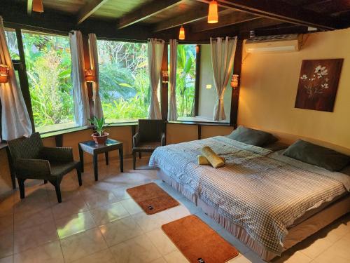 a bedroom with a bed and two chairs and windows at RELAX ECO Life Center-Khao Lak in Khao Lak