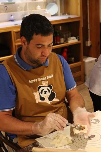 a man in a kitchen preparing food with a knife at Happy Dragon City Center Alley Hotel -In the city center with big window&heater, ticket service&Free Coffee&Food recommendation,Near Tian Anmen Forbiddencity,Easy to get traditional Walking area&Shichahai in Beijing