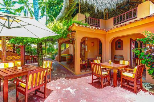 a restaurant with wooden tables and chairs and an umbrella at CAMPO DEL MAR - STUDIOS and SUITES - LOS CORALES beach in Punta Cana