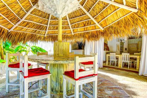 a dining room with a table and chairs under a straw umbrella at CAMPO DEL MAR - STUDIOS and SUITES - LOS CORALES beach in Punta Cana