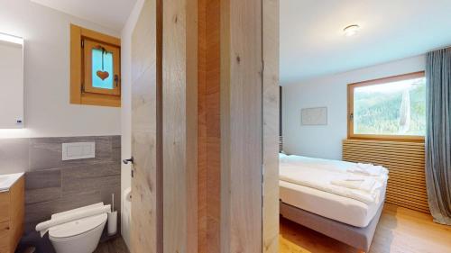 a bathroom with a bed and a toilet and a window at Abitaziun Traval - Zuoz in Zuoz