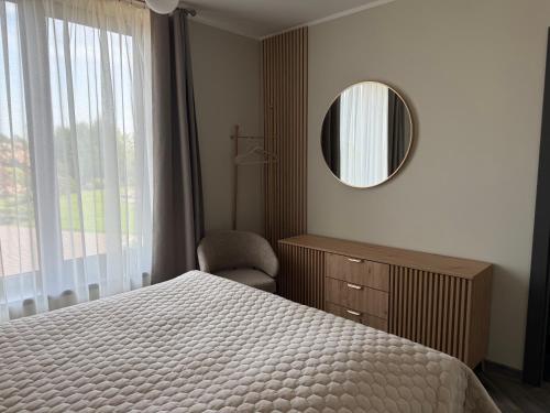 a bedroom with a bed and a mirror and a chair at Lauras in Bauska