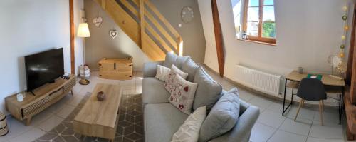 a living room with a couch and a tv at Les Toits de Mittelwihr proche Colmar, Ribeauvillé in Mittelwihr