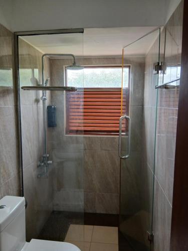 ein Badezimmer mit Glasdusche und Toilette in der Unterkunft A Wood's View Villa in Kandy