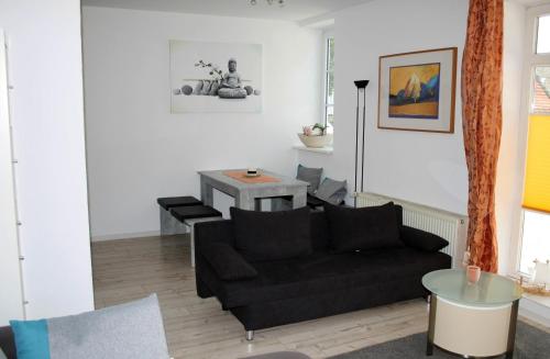 a living room with a black couch and a table at Auszeit im Eibenhaus in Schieder-Schwalenberg
