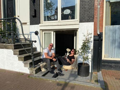 2 personnes assises sur les marches d'un immeuble dans l'établissement JoyJoyJoy the White Wilde ecolicious studio in a historic Canalhouse from 1799 with terrace at the canals, à Amsterdam