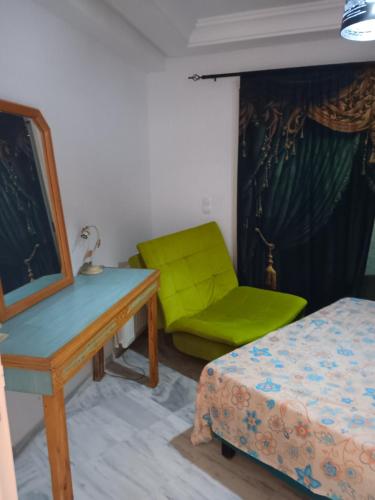 a bedroom with a desk and a green chair at Najla in Hergla