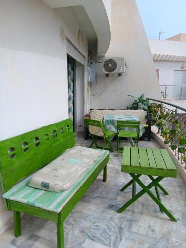 a patio with green benches and tables on a balcony at Najla in Hergla