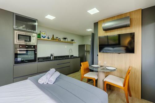 a bedroom with a bed and a kitchen with a table at Novíssimo: Go Carlos Gomes - Infra estrutura e Vista Espetacular! in Porto Alegre