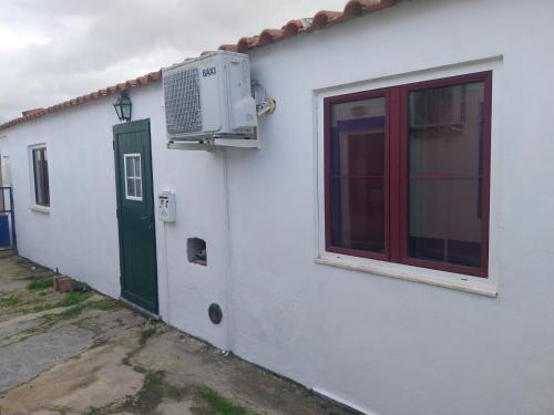 a white house with a green door and a window at Casa Santa Maria - apartamento C in Ermidas