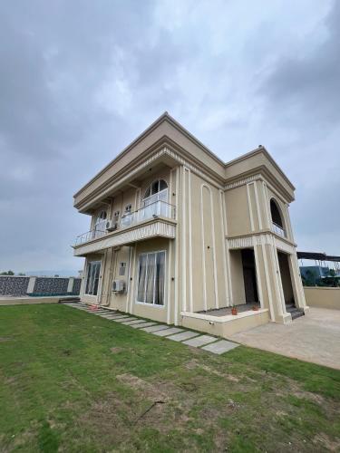 a large white house with a large yard at Royal Elite - 6BHK Luxury Villa by Royal Villa Lonavla in Lonavala