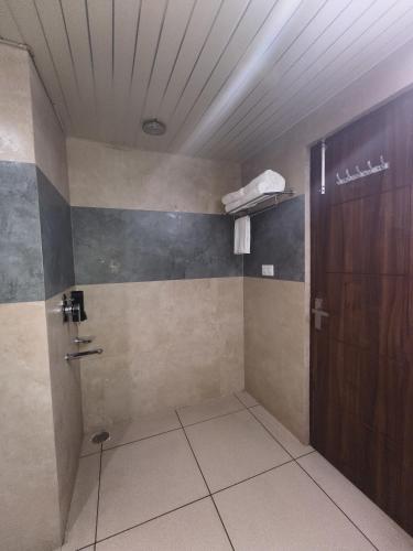 a bathroom with a shower and a wooden door at Aliza Inn And Suites By SRS Hotels in Dharamshala