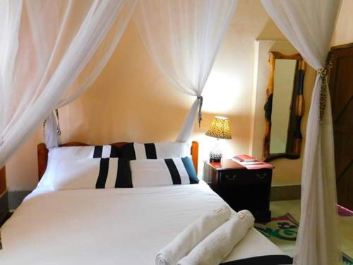 a bedroom with a white bed with black and white pillows at Kivu Resort in Nakuru