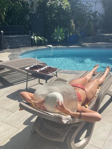 a woman in a hat laying on a chair next to a swimming pool at Chambres d'hôtes du domaine des doudous in Saint-Pierre