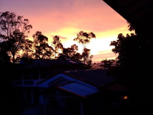 a sunset with trees and houses in the foreground at Luana Holiday Bungalow in Bandarawela