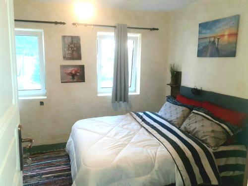 a bedroom with a bed and two windows at Stone House Rooms near Kavala in Amisianá