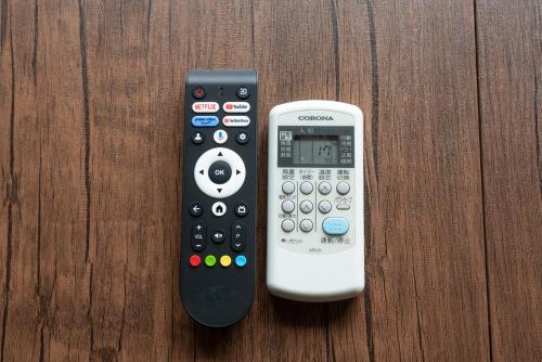 two remote controls sitting on a wooden table at 成田空港直通で97平米で13名宿泊駅徒歩11分の日本スタイル in Yachiyo