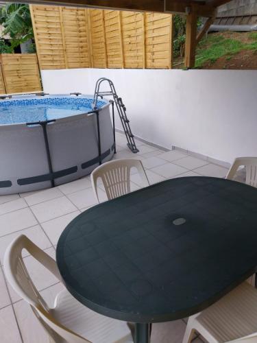 a black table and chairs and a swimming pool at Frédovacances logement iGloo-LOVE in Rivière-Pilote