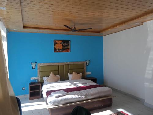 a bedroom with a bed with a blue wall at Elite Peak Hotel in Kasauli