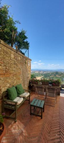un patio avec deux bancs et un mur de briques dans l'établissement La Casa di Angela, à Montepulciano