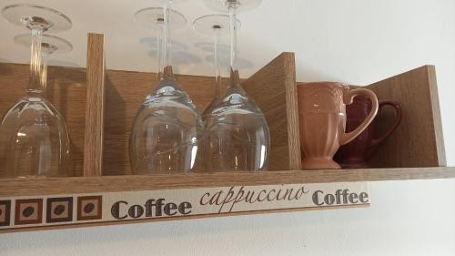 a wooden shelf with glass wine glasses and a cup at Auszeit im Eibenhaus in Schieder-Schwalenberg