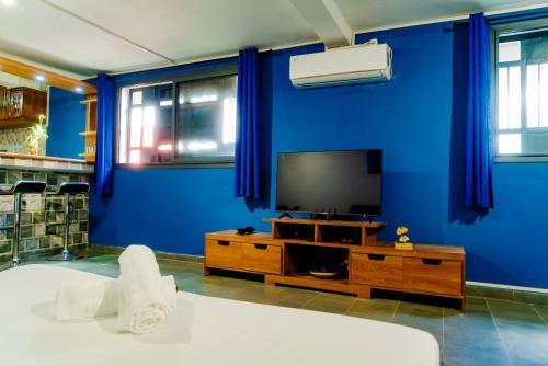 a living room with a blue wall and a tv at Cattleya Guest house in Hell-Ville