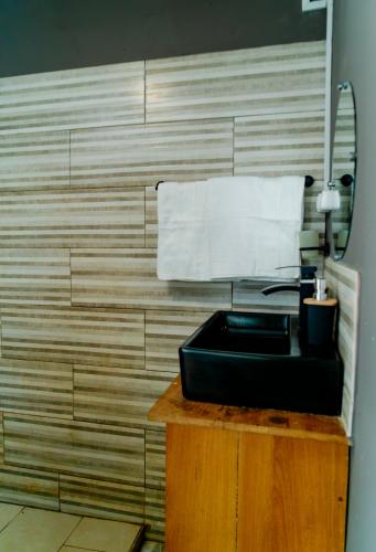 a bathroom with a black sink and a mirror at Cattleya Guest house in Hell-Ville
