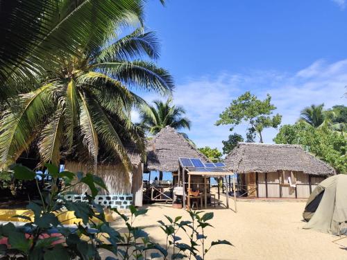 a house on the beach with a palm tree at Lokobe eco lodge in Nosy Be