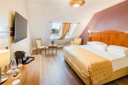 a hotel room with a bed and a table and chairs at Hotel Josefshof am Rathaus in Vienna