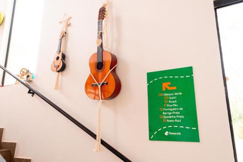 two acoustic guitars hanging on a wall with a sign at Pousada Passarada - Tudo novinho te esperando in Pirenópolis