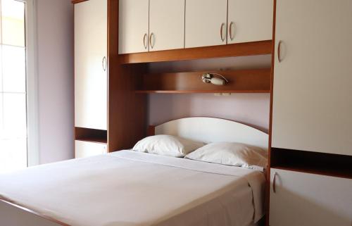a bedroom with a white bed and white cabinets at Apartmani California in Starigrad-Paklenica
