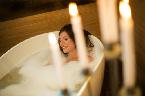 a woman sitting in a bath tub with candles at Burghotel Nürnberg in Nuremberg