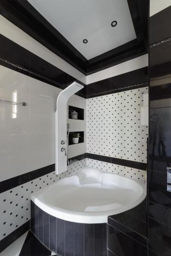 a bath tub in a bathroom with black and white tiles at Villa Under Meteora in Kalabaka