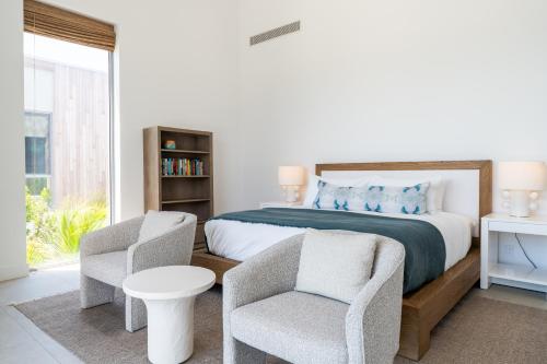 a bedroom with a bed and two chairs at South Bank in Long Bay Hills