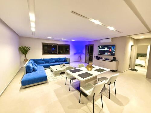 a living room with a blue couch and a table and chairs at Luxury Apartment with Pool & Parking in Tamraght 10 mn from Taghazout in Tamraght Ouzdar