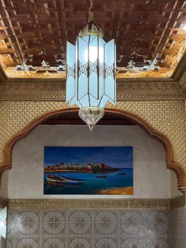 a chandelier hanging from a ceiling with a painting at Riad Shama in Rabat