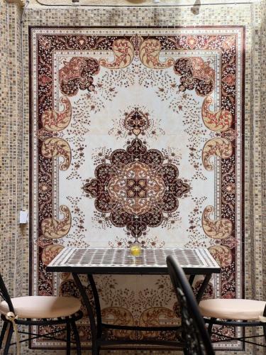a table with chairs in front of a wall at Riad Shama in Rabat