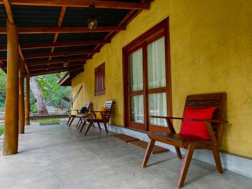 a porch of a house with chairs and a red pillow at Elephant Fence Habarana in Habarana