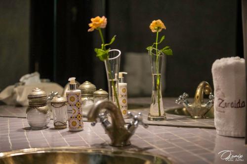 a bathroom counter with a sink and vases with flowers at Riad Zoraida in Marrakech