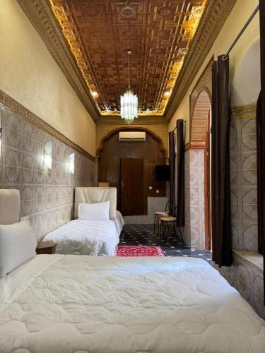 a bedroom with two beds and a chandelier at Riad Shama in Rabat