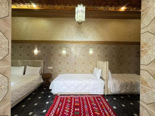 a bedroom with two beds and a red rug at Riad Shama in Rabat
