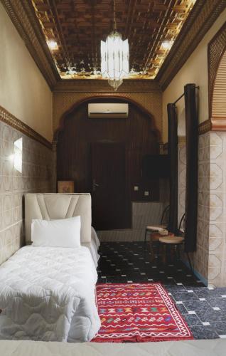 a bedroom with a white bed and a chandelier at Riad Shama in Rabat