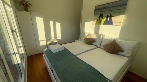 a small bedroom with a bed with white sheets and pillows at Grosse Terrasse mit Privatsphäre & Aussendusche in Siebnen